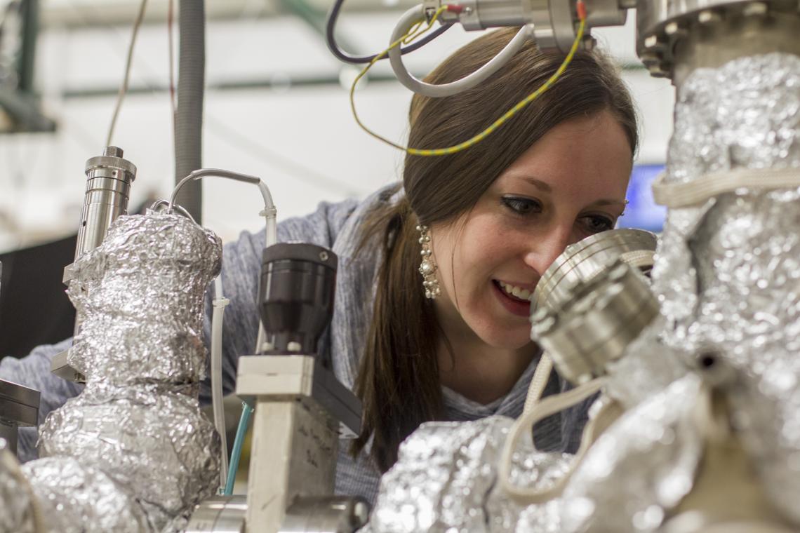 Calley Eads inspects a sample in the vacuum chamber to get it ready for measurement. Calley Eads inspects a sample in the vacuum chamber to get it ready for measurement.